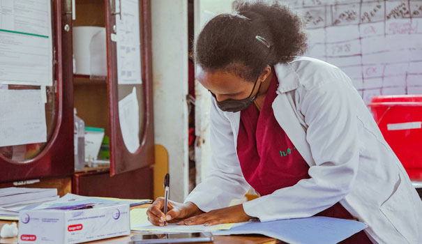 A doctor writing notes in an office.