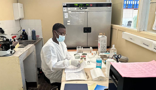 A researcher wearing a mask reading at analysis results in a laboratory.