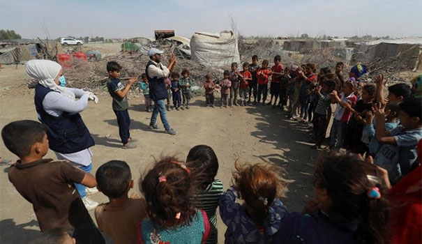 A doctor speaking to children standing in a semi circle.