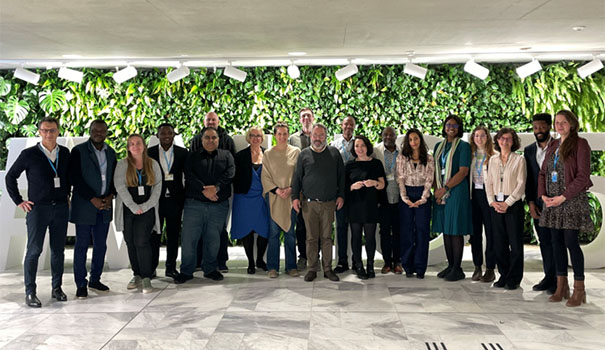 Participants standing in a row being photographed infront of plants.