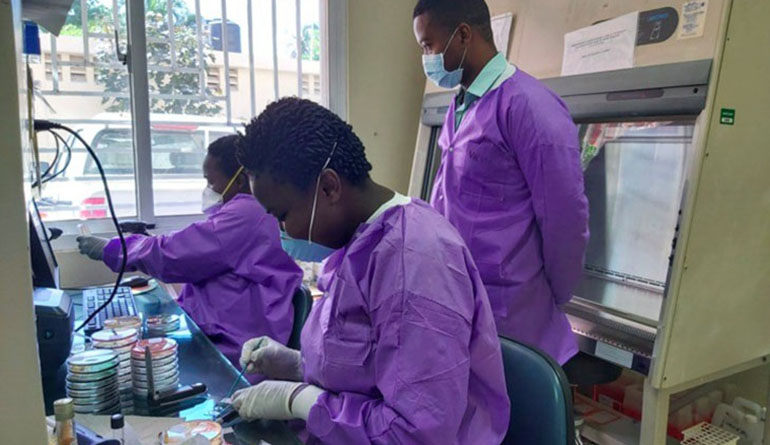 Bab technians dressed in mauve working in a laboratory