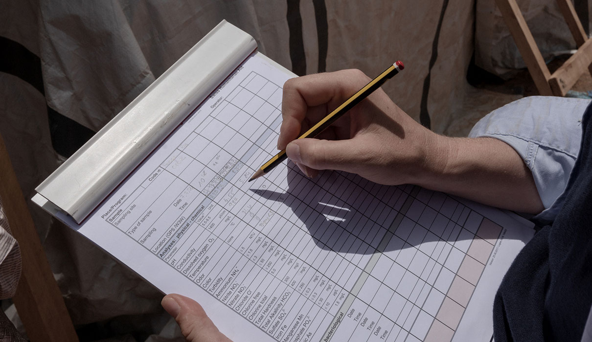 Hand holiding pencil fillingin sample form.